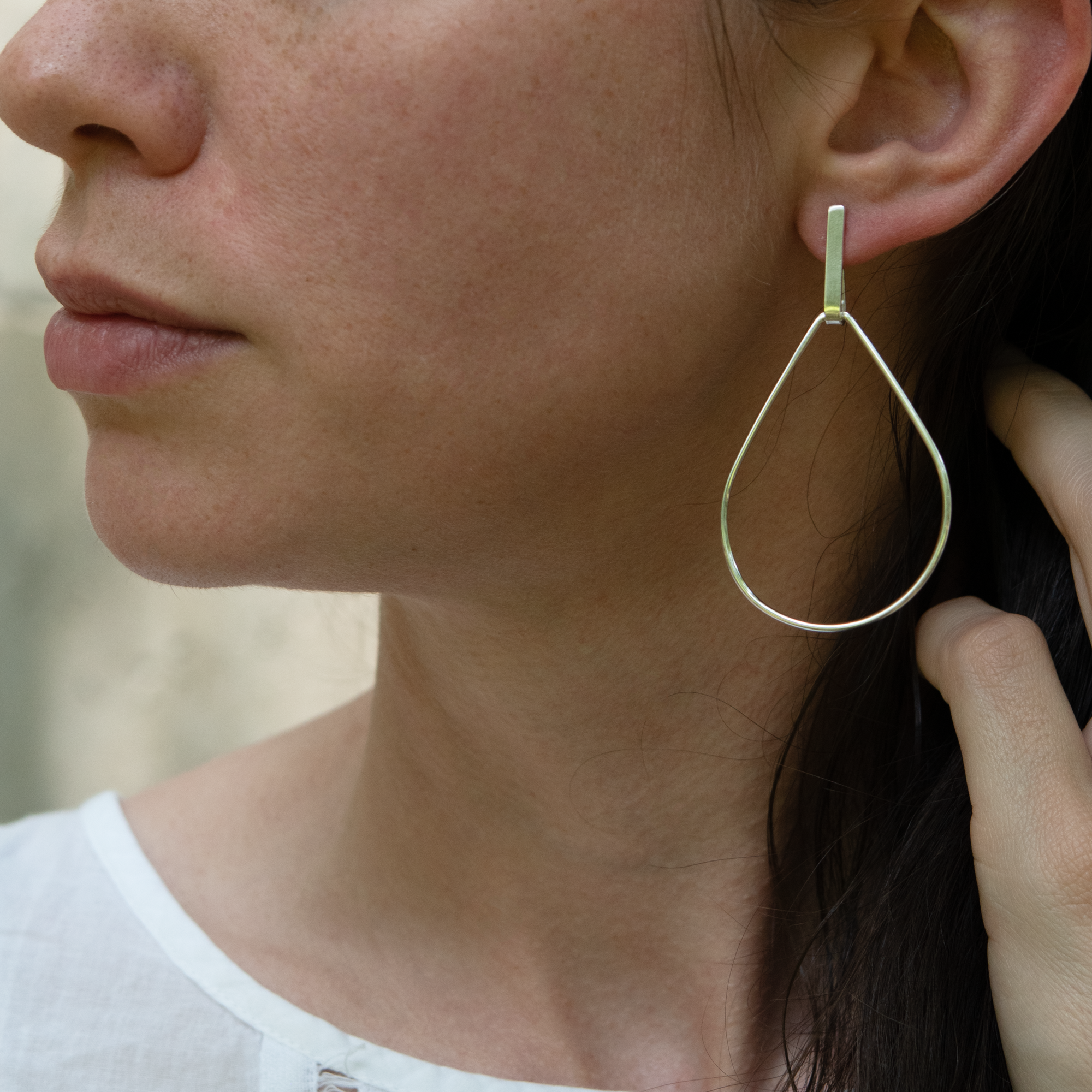An image of a model wearing the newest version of an LHMS classic - sterling silver teardrop earrings with a hand fabricated drop bar. 