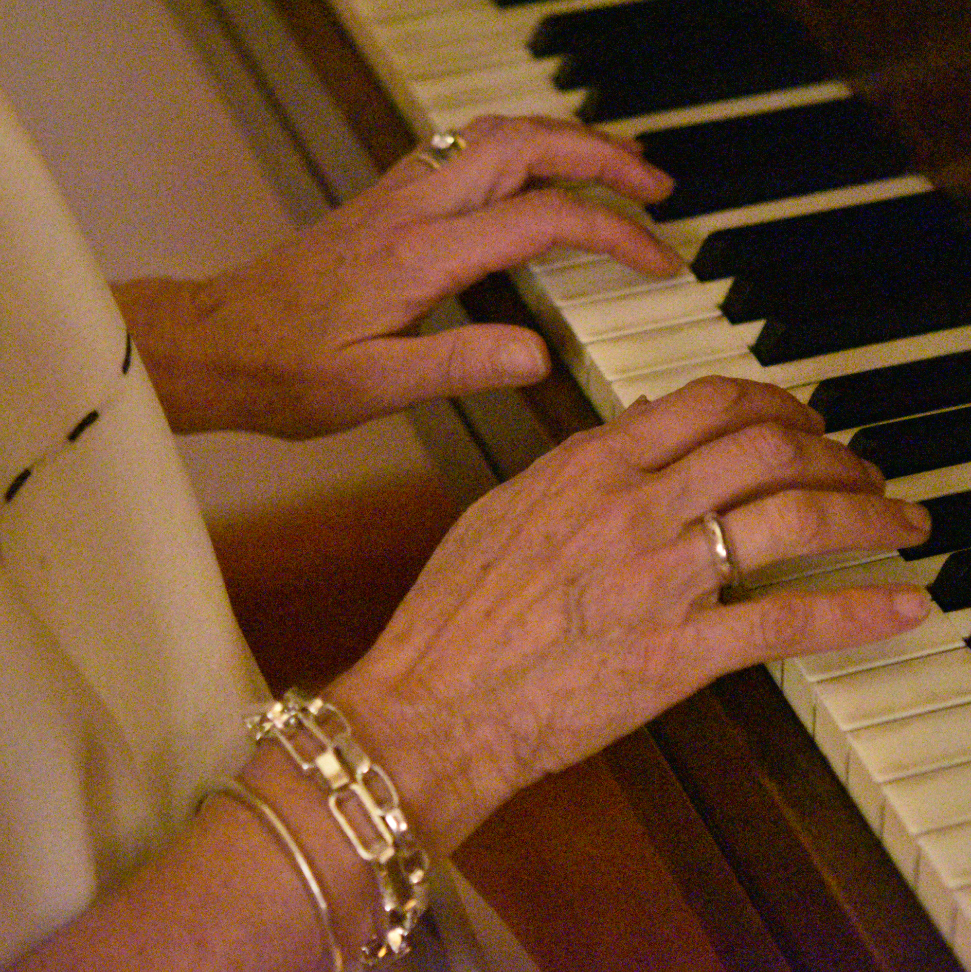 Liz playing piano with the theo, greta, and cast bangle bracelets prominent on her hand.