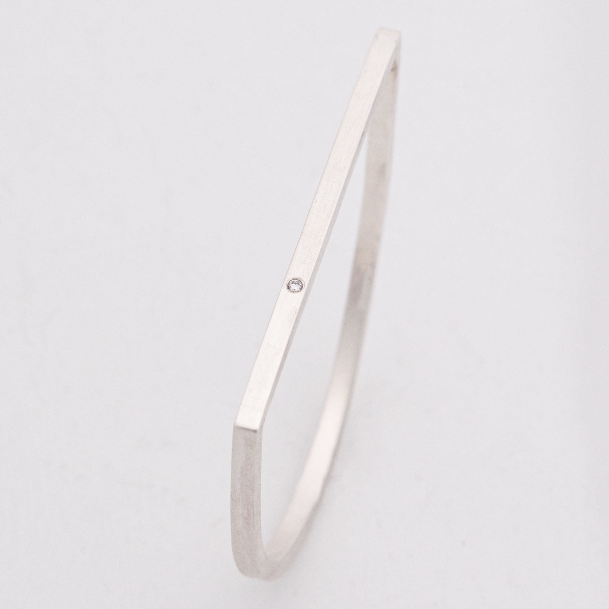 An image of the sterling silver c bar bracelet with a 2.5 mm diamond set in the flat edge of the bangle. 
