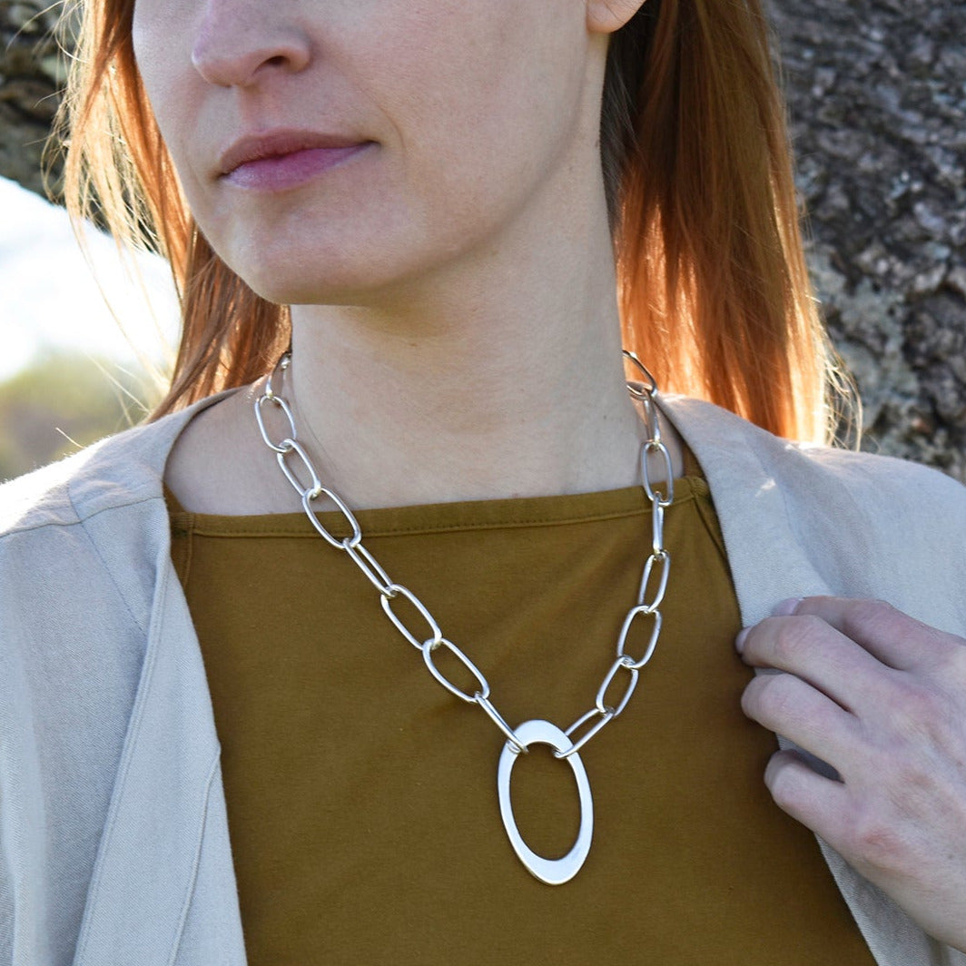 A model wearing the new style Fiona necklace, featuring a large central oval anchoring an entirely hand crafted chain collar.