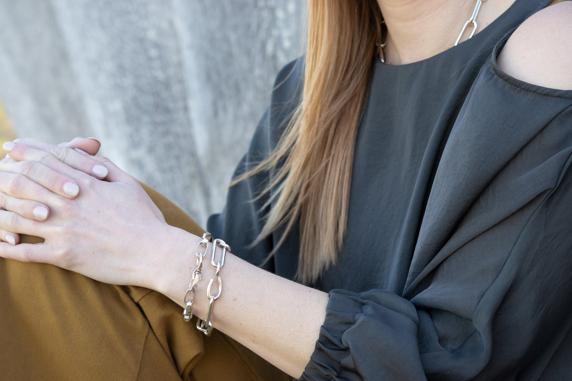 A model wearing both the Eliza Chain Bracelet and the Greta Bracelet stacked together.