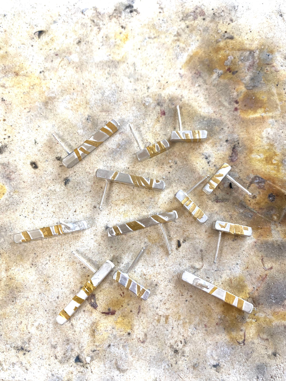 A photo of several Gold Fusion Collection bar earrings on the soldering block, awaiting oxidation.