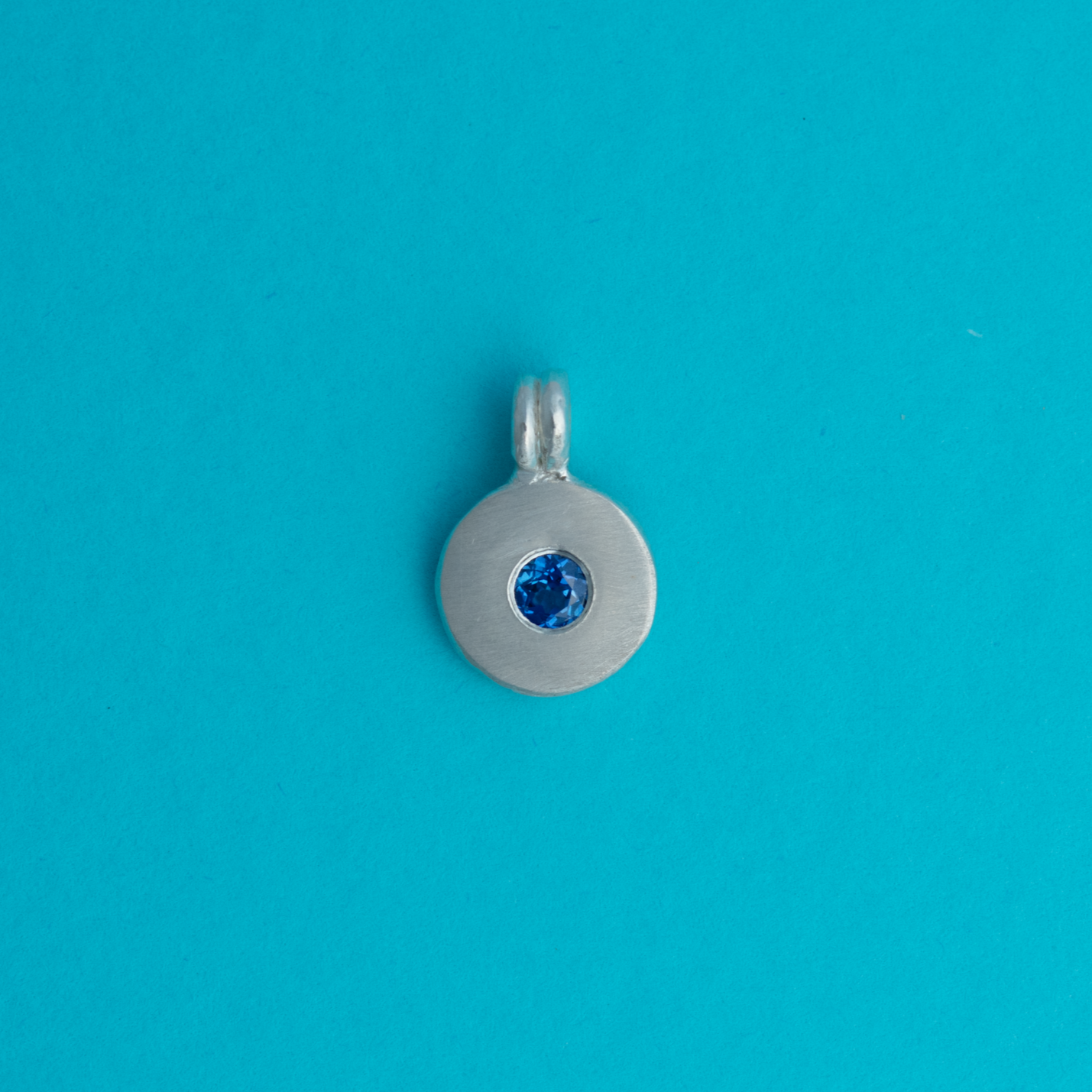 Silver pendant with a blue sapphire lab grown gemstone on a bright background