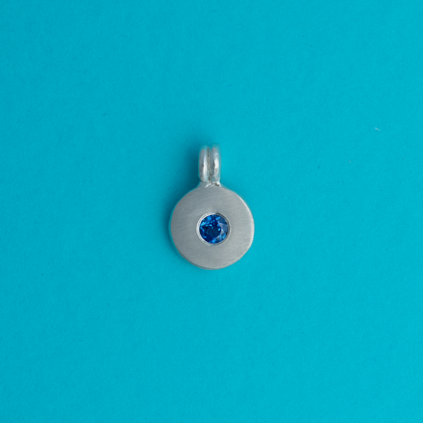 Silver pendant with a blue sapphire lab grown gemstone on a bright background