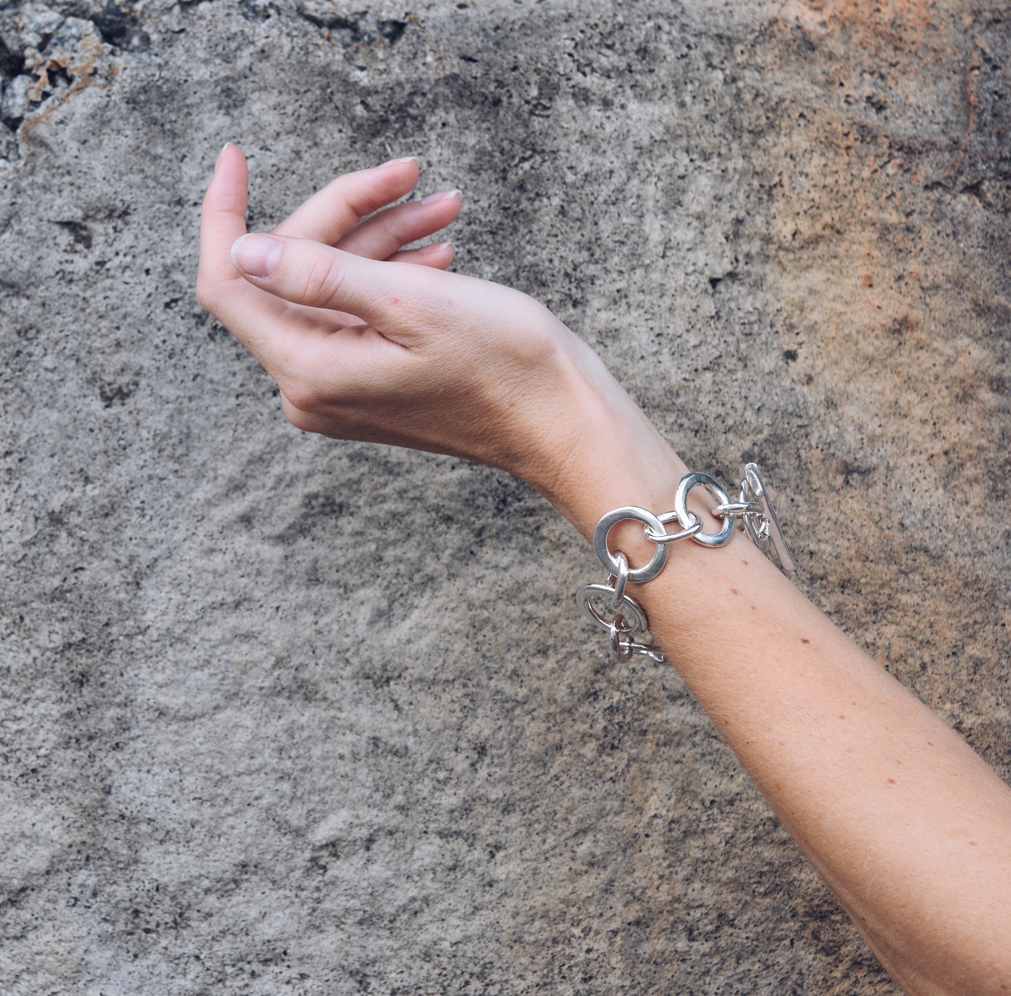A model wearing the Caroline bracelet with a concrete background.