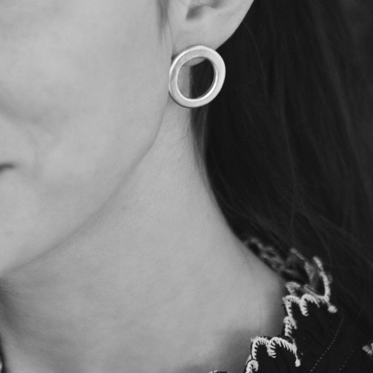 The Caroline link earring on a model for scale. These solid cast sterling silver circles have a sculptural element and are on sterling silver posts.