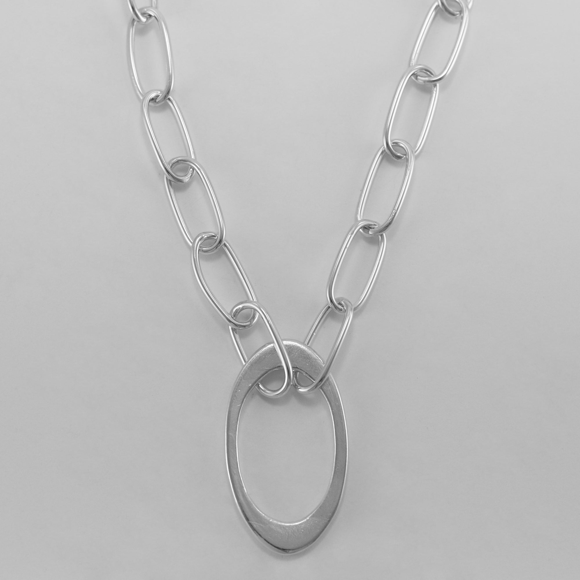 An up close image of the fiona necklace with the central cast oval and handcrafted chain around the collar.