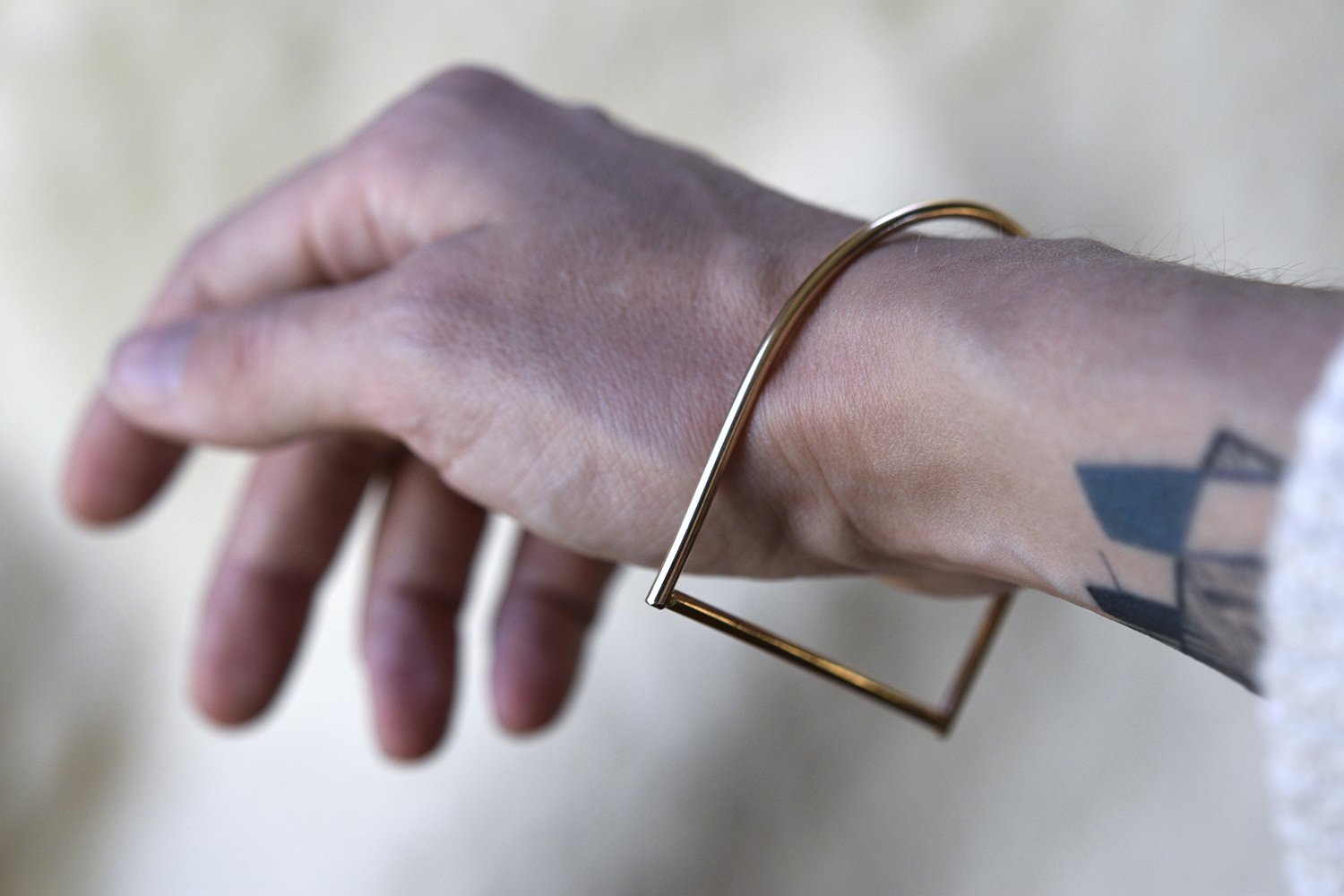 Close up shot of the 18 karat gold C Bar bangle on a wrist for scale. The C Bar is an edgy take on the classic bangle. 