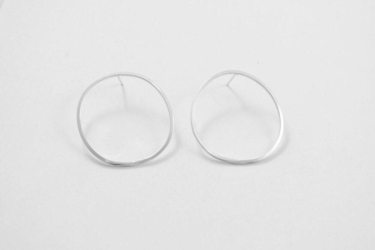 Large circle earrings are made with squared off sterling silver wire on a post. An updated take on a classic hoop.
