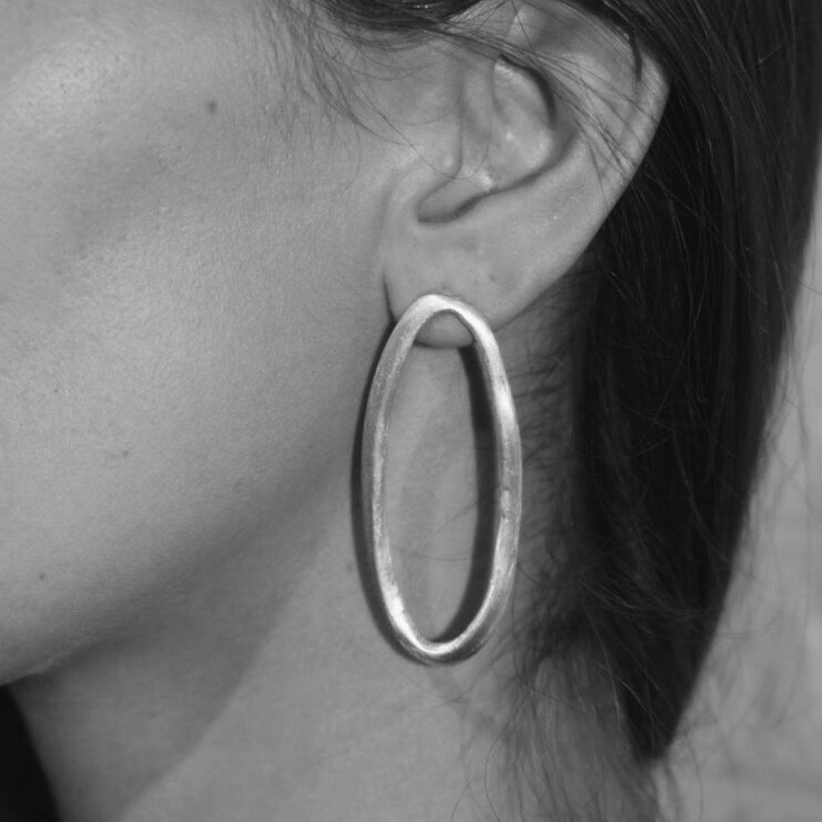 Image shows the Organic Oval Earrings on a model for scale.