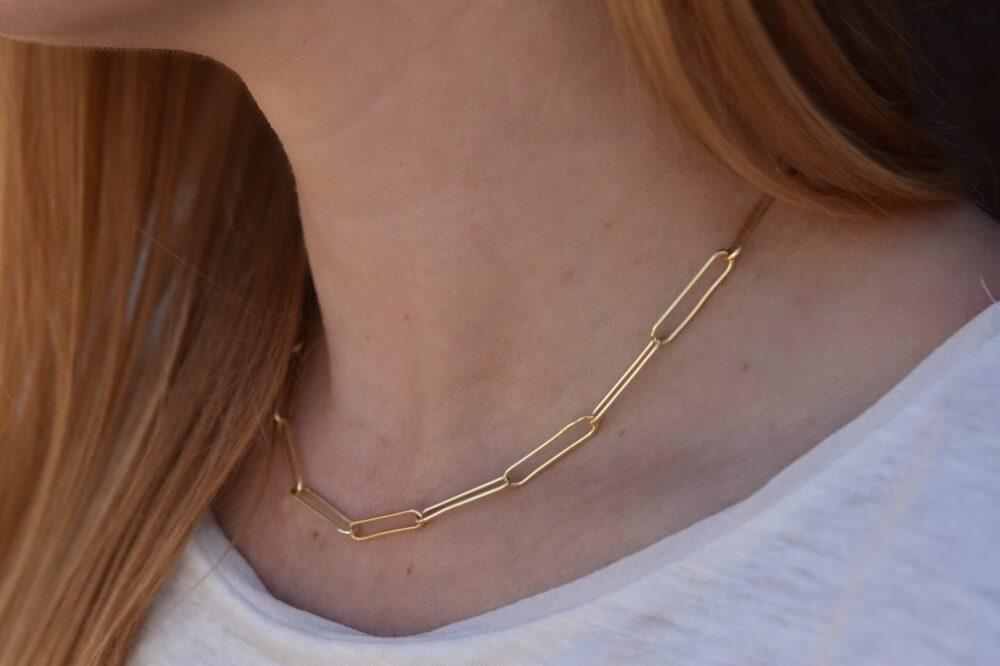 Image shows a close up view of the elongated oval links of the Paperclip Necklace on a model for scale.