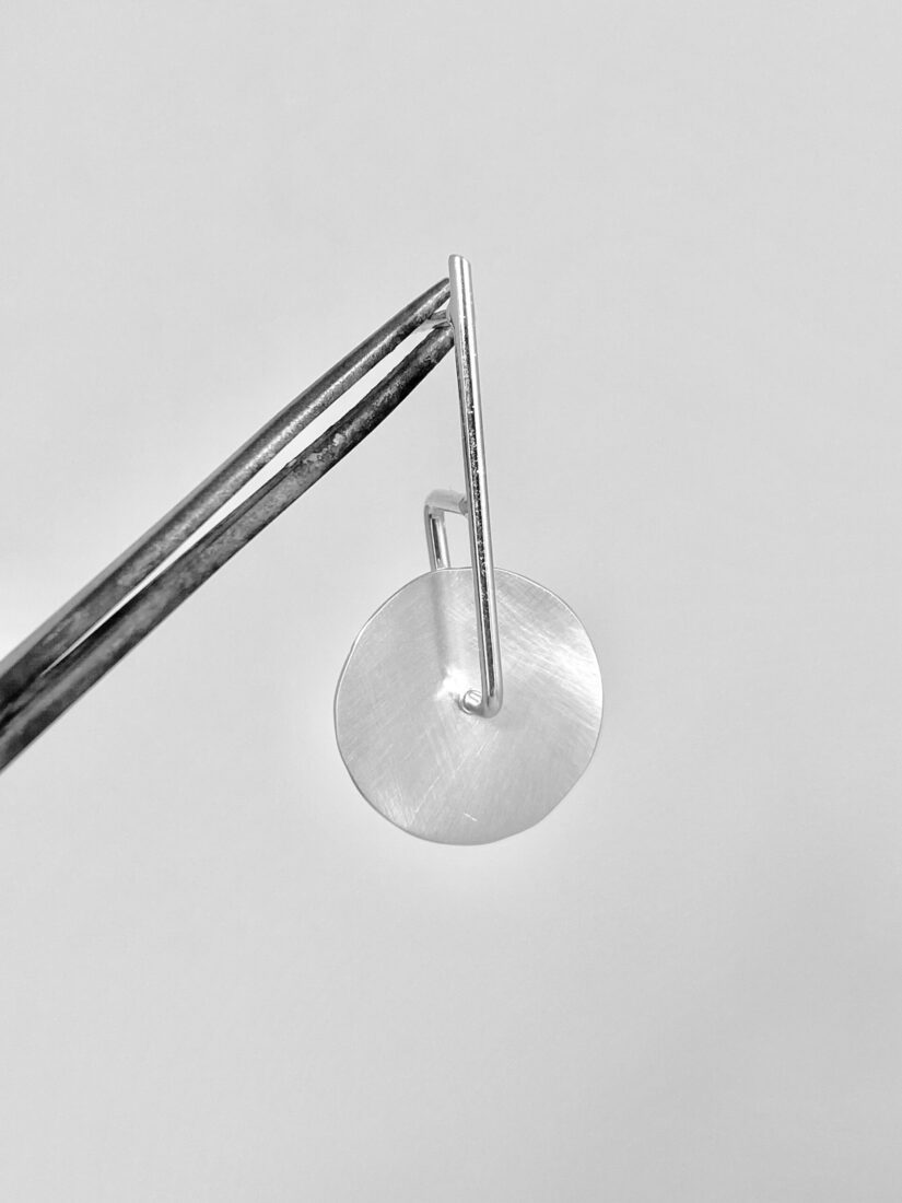 Small Twirling Disc suspended from metalsmithing pliers to emphasize the movement of the twirling disc