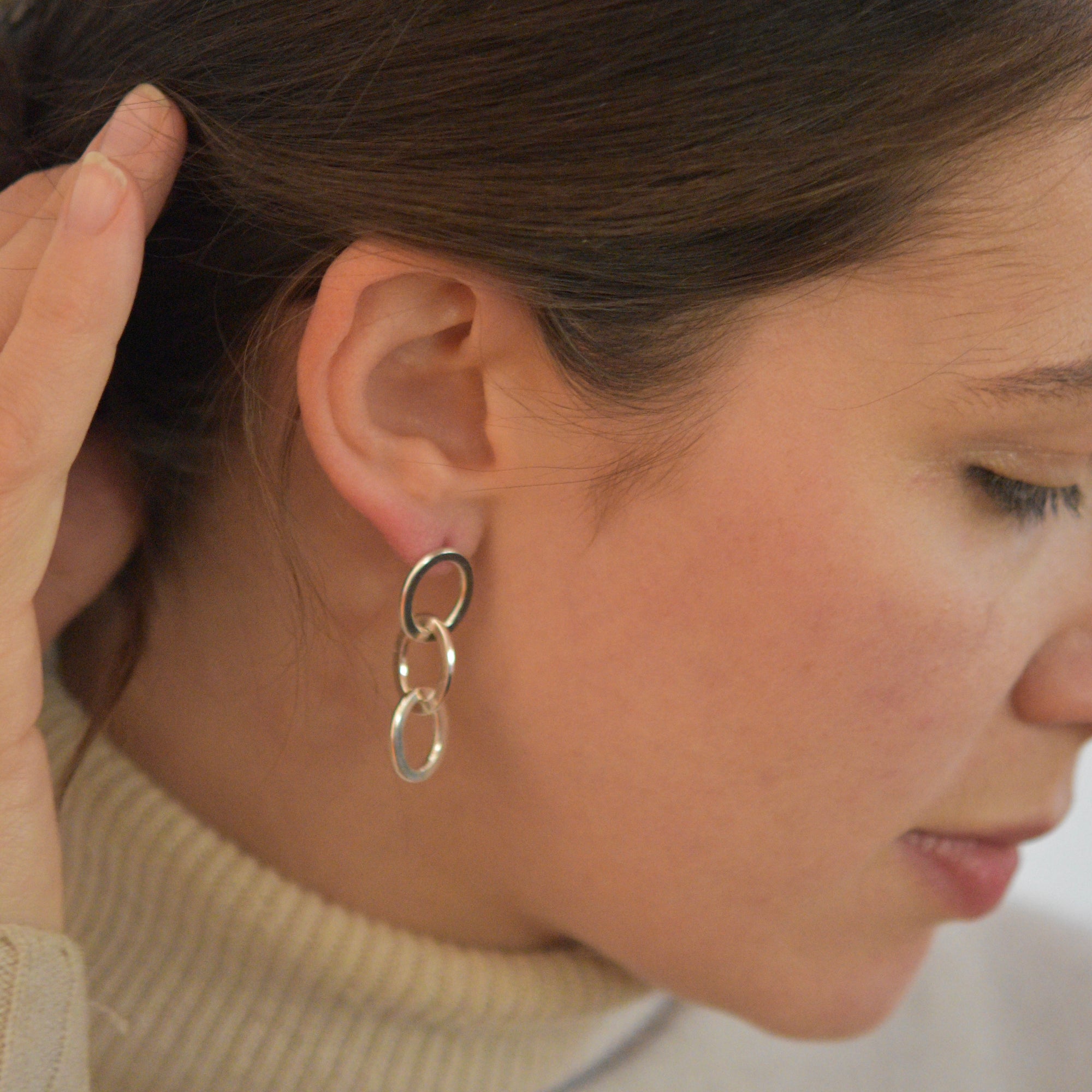 Image of the flattened triple link earrings on a model for scale.