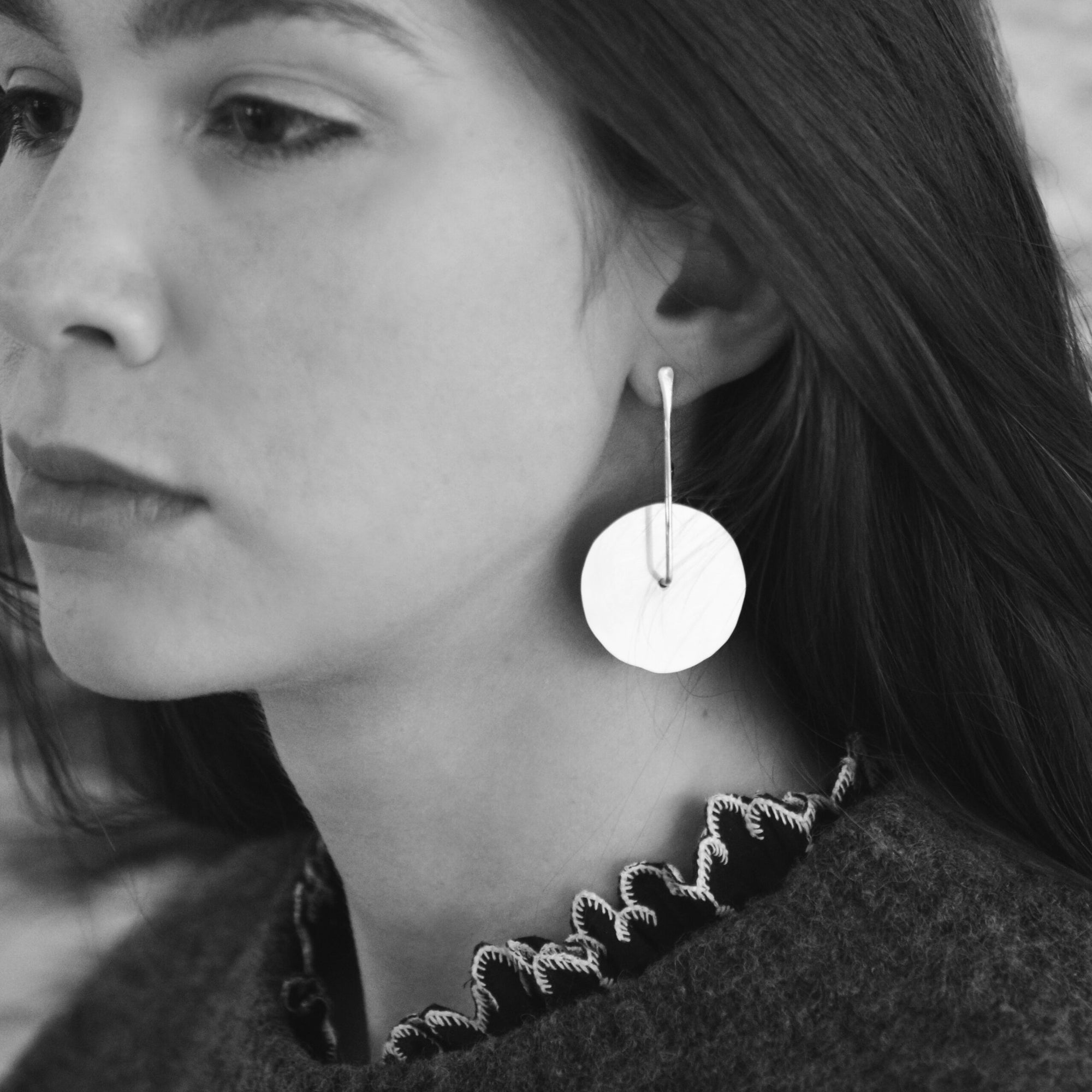 Image shows large size twirling disc earrings on a model for scale.